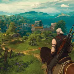 Geralt na koniu podziwia krajobraz z kwitnącymi słonecznikami, w oddali widać miasteczko. W tle góry i jezioro.