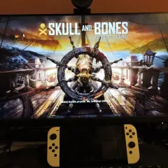 Logo gry "Skull and Bones" z kołem sterowym ozdobionym czaszką i kośćmi.