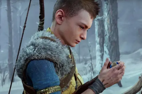 Atreus, zamyślony, trzyma w dłoni magiczny kamień. W tle zimowy las.