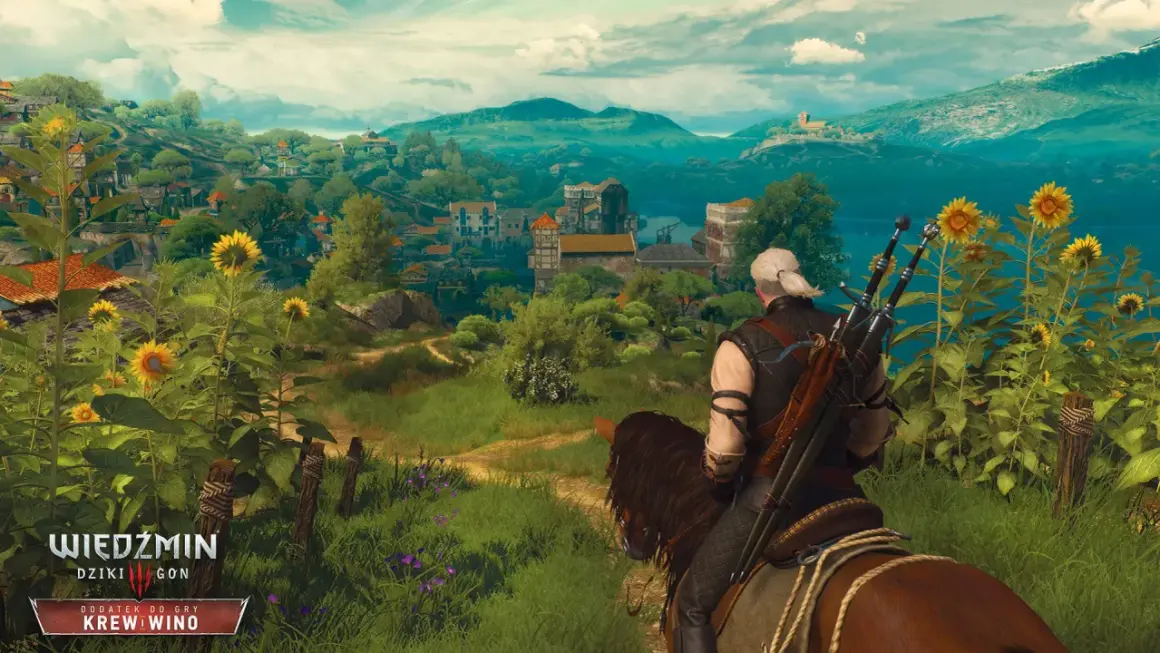 Geralt na koniu podziwia krajobraz z kwitnącymi słonecznikami, w oddali widać miasteczko. W tle góry i jezioro.
