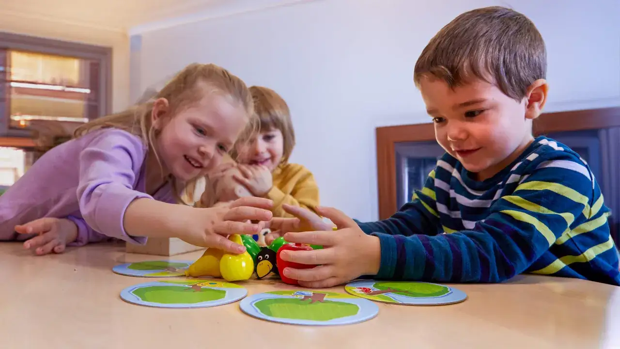 Dzieci grają w gry coop, próbując zebrać owoce. Radość i skupienie na ich twarzach.