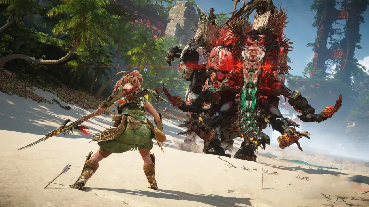 Aloy z Horizon Zero Dawn 2 walczy z mechanicznym potworem na piaszczystej plaży, otoczonej bujną roślinnością.