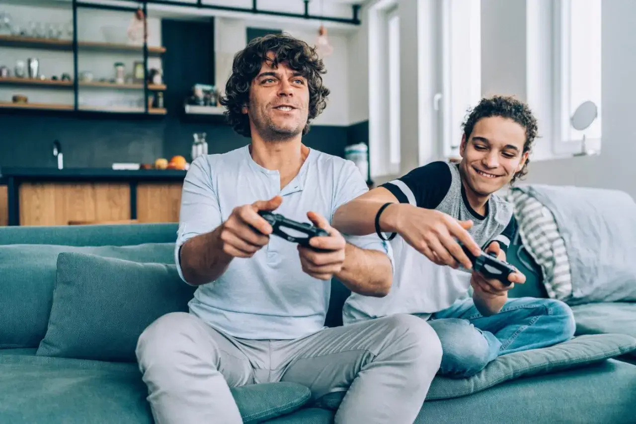 Ojciec i syn grają w gry na PS4. Szukacie ps4 gry dla dzieci za darmo? To świetna zabawa dla całej rodziny!