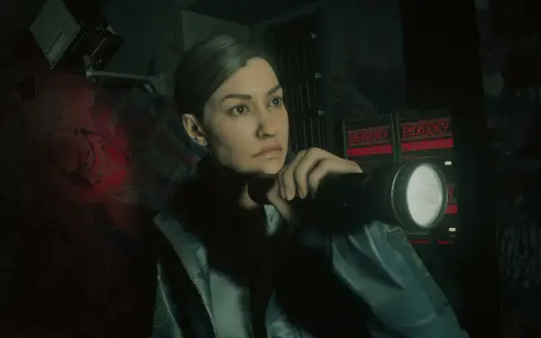 Saga Alan Wake 2 DLC: Agentka z latarką bada mroczne korytarze, gdzie migają czerwone napisy "EMERGENCY - SEEK SHELTER".